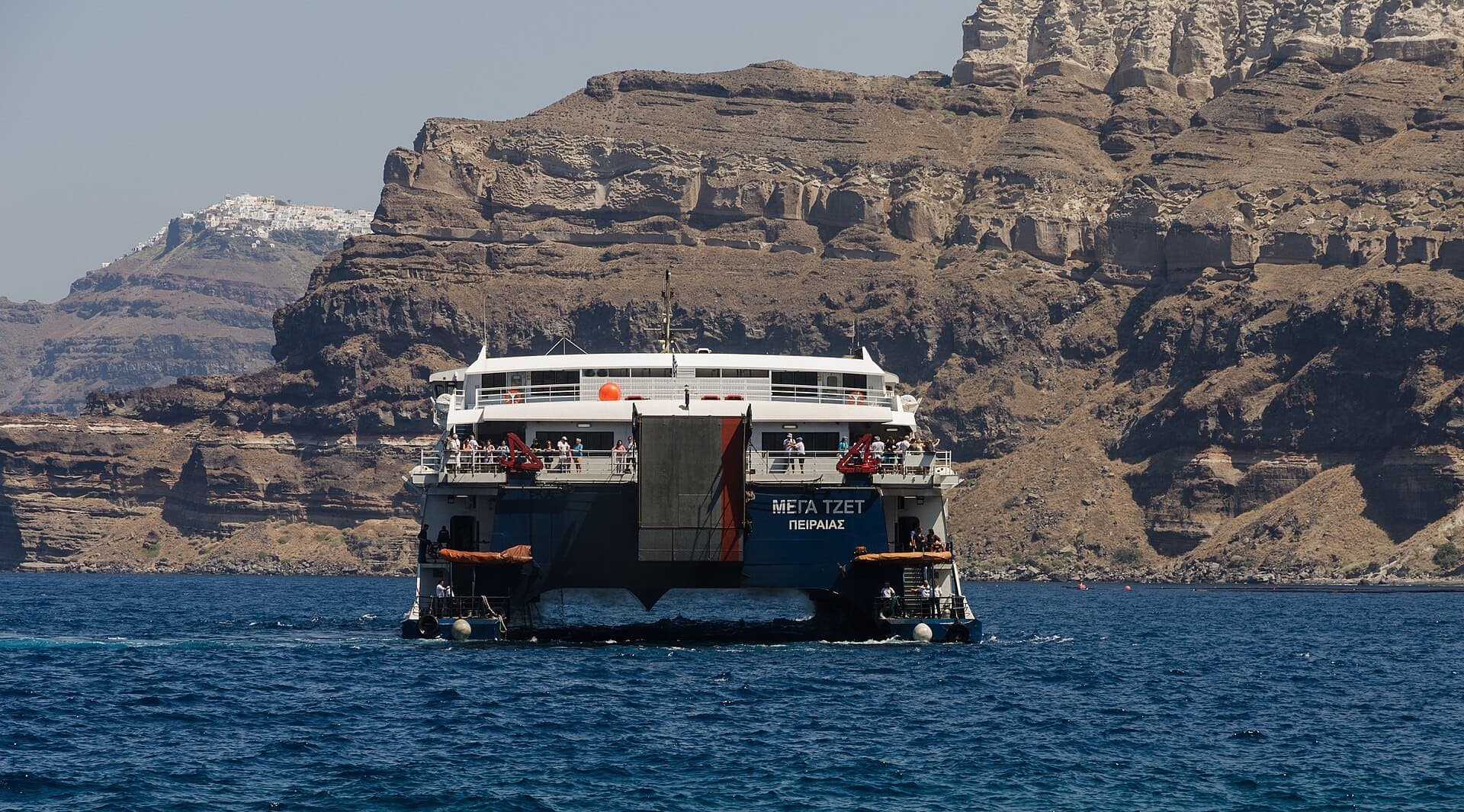 A ferry arriving at Santorini beneath the caldera cliffs