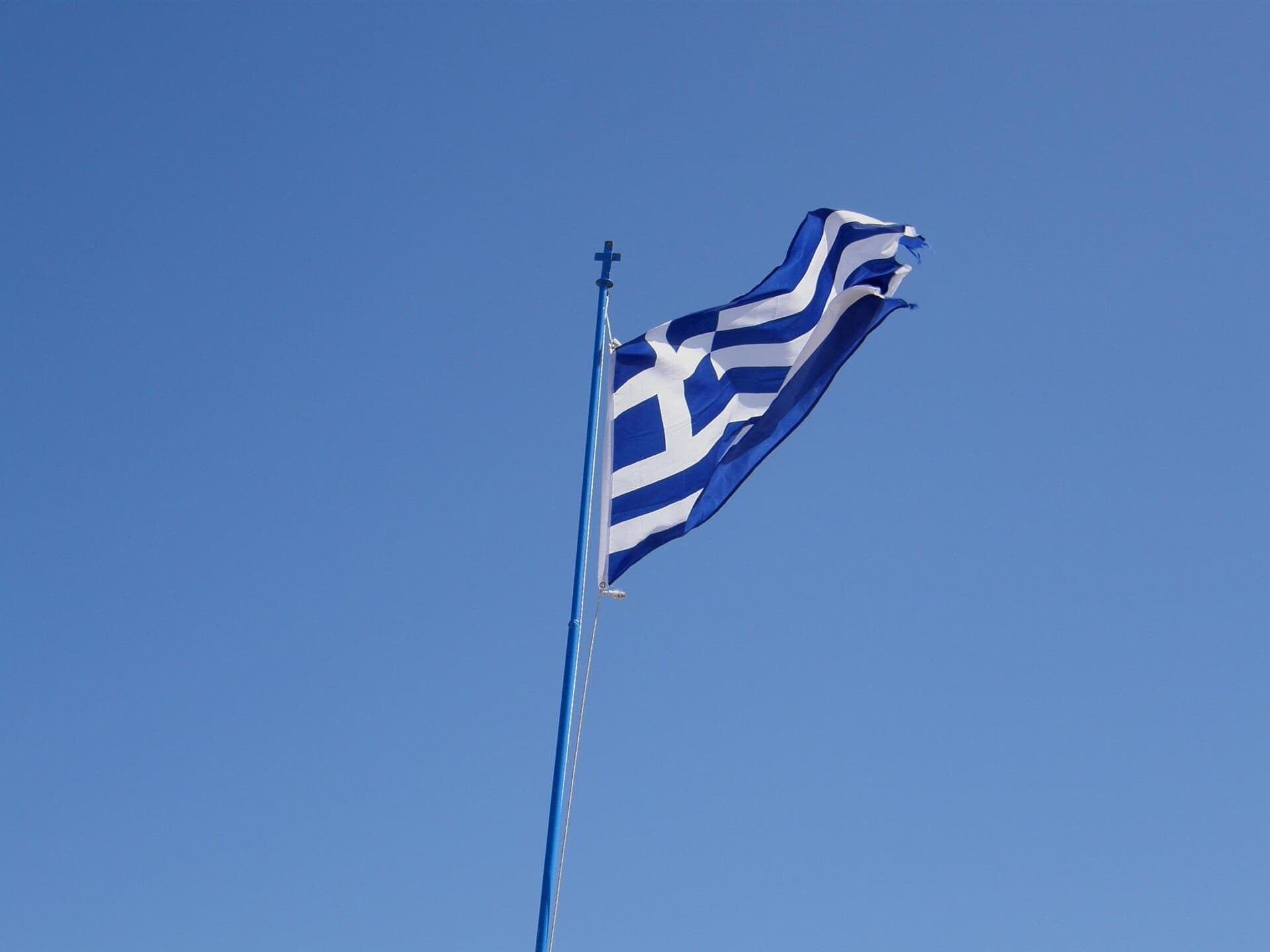 The Greek flag flying against a blue sky