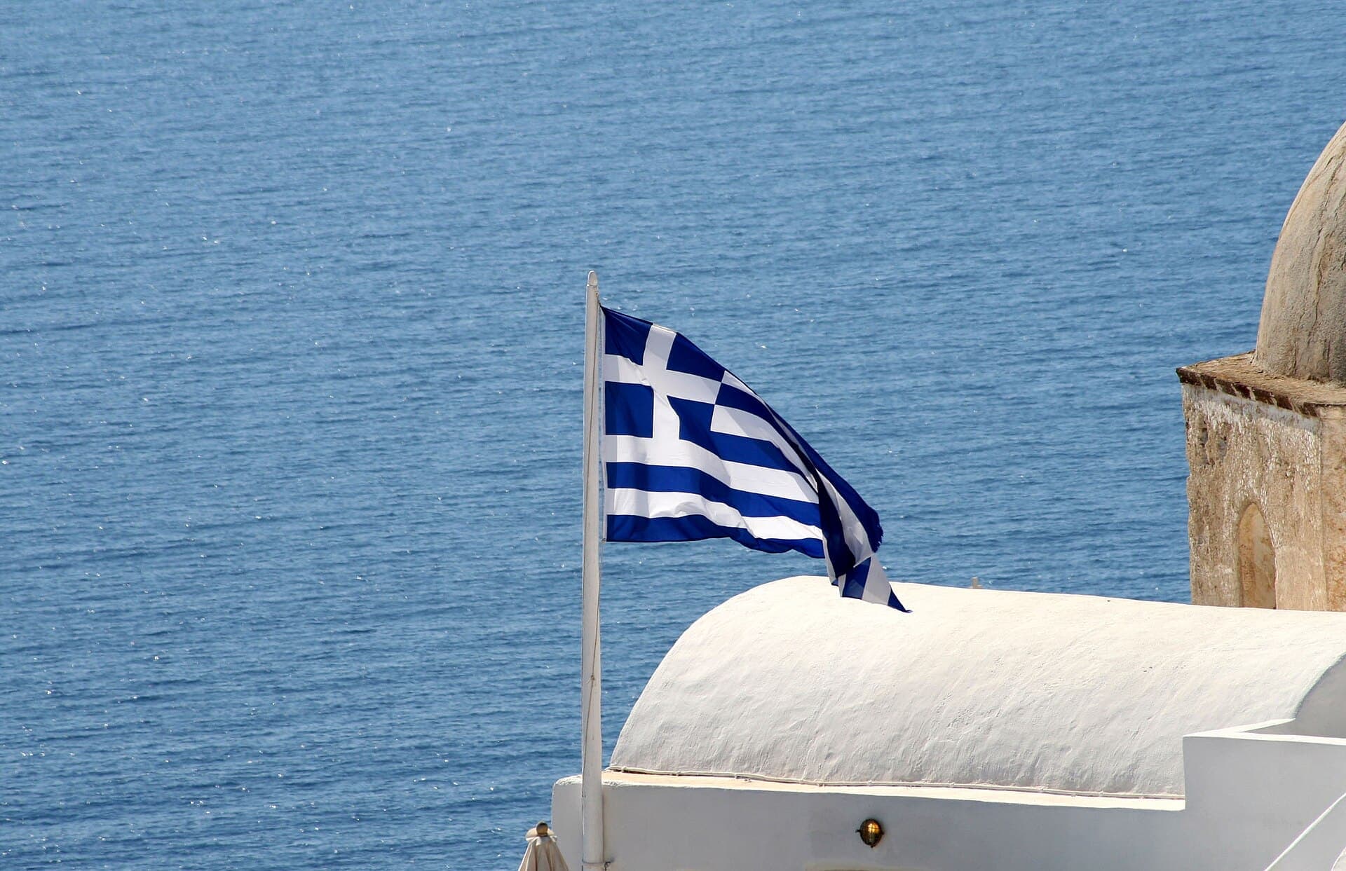 A Greek flag over the Aegean on Santorini
