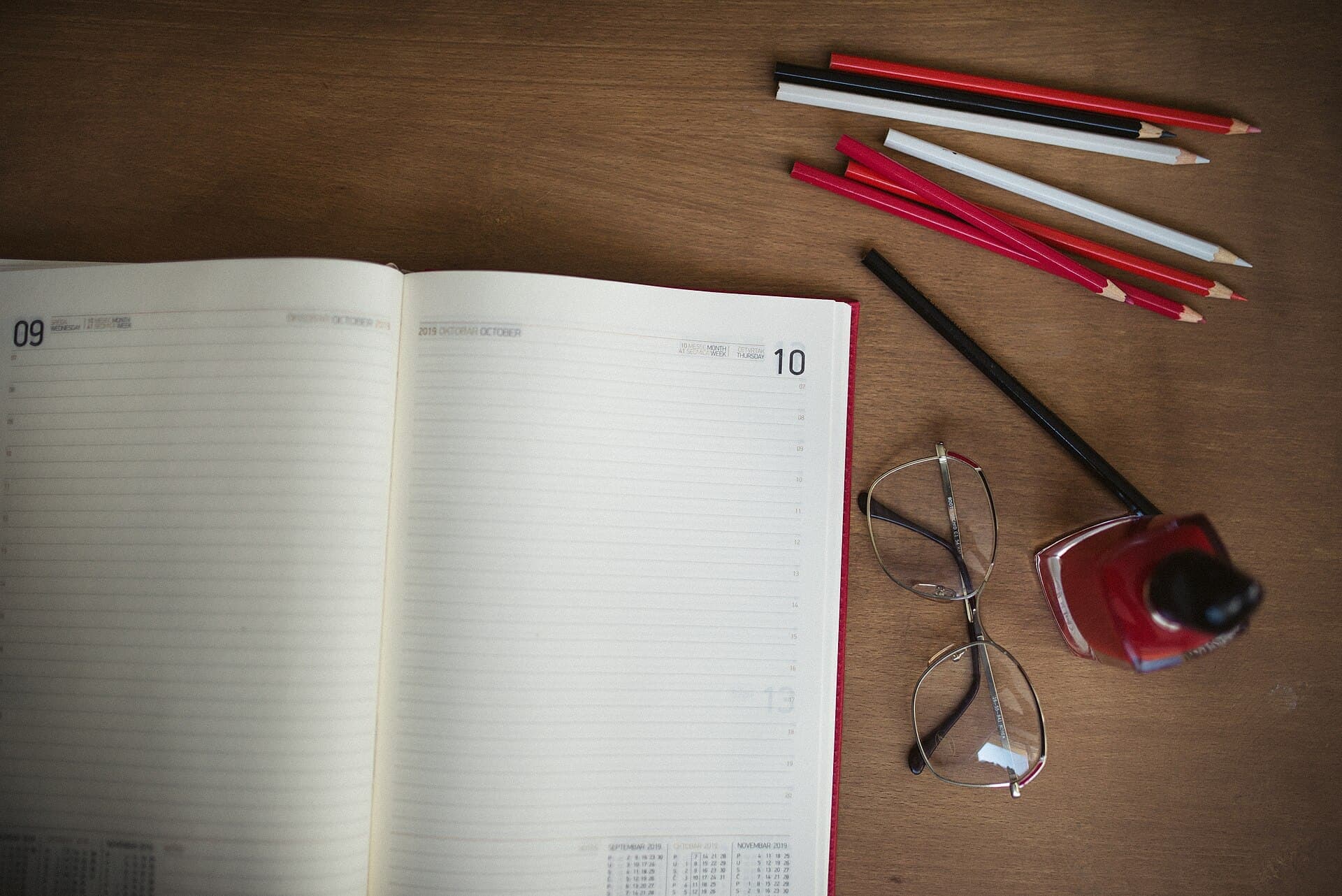 A planner, pencils and glasses on a desk