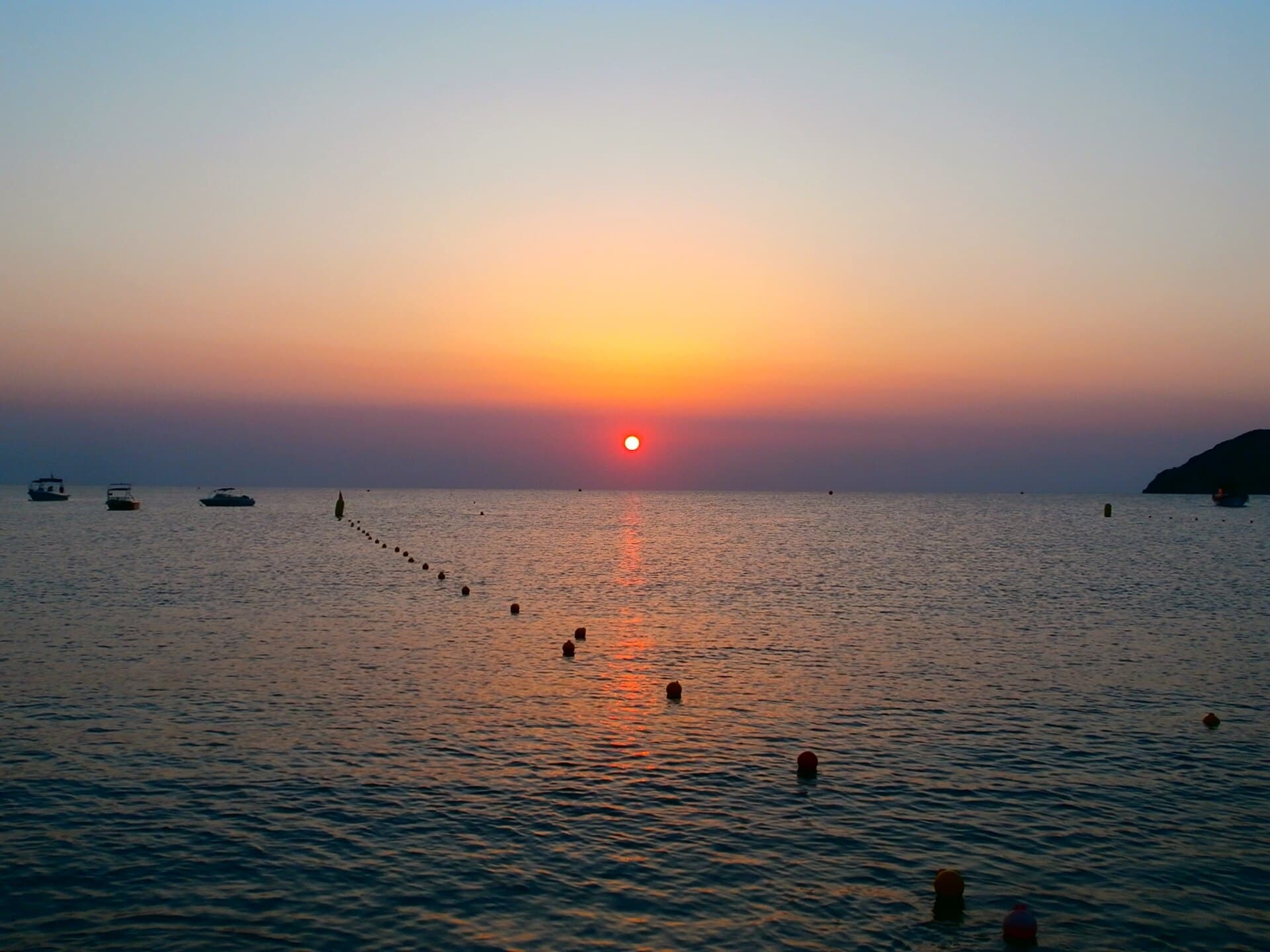 Sunrise over the sea with early swimmers